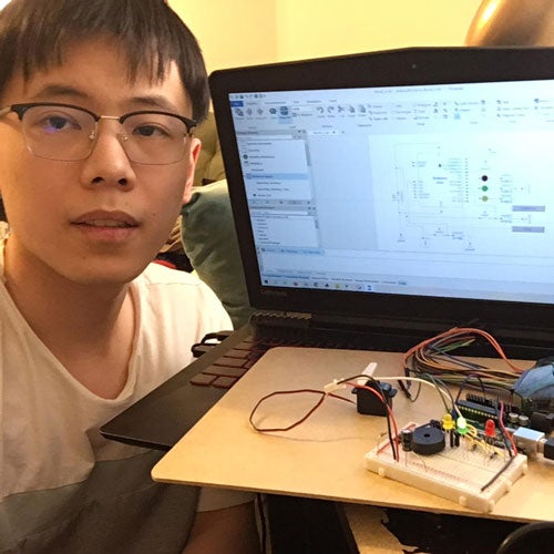 Student poses in front of laptop connected to different circuits